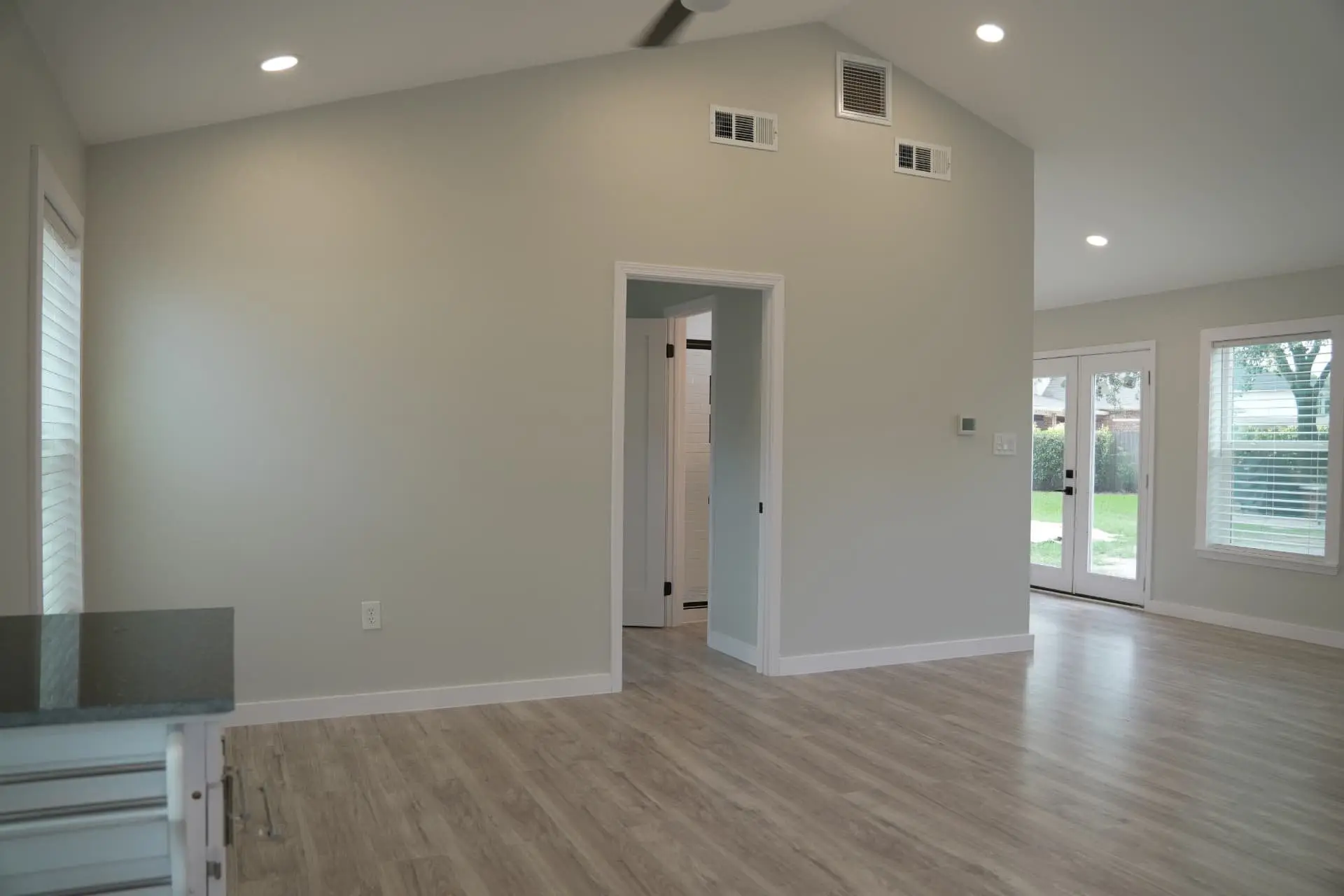 Vaulted living area with wood-look floors and French doors to the yard