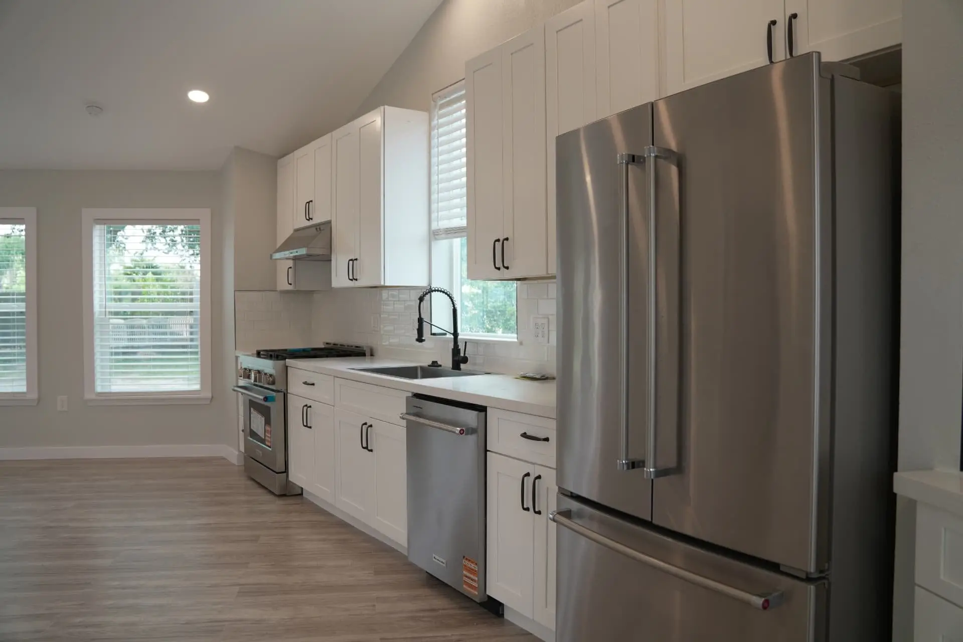 Kitchen with white shaker cabinets, stainless appliances and quartz counters