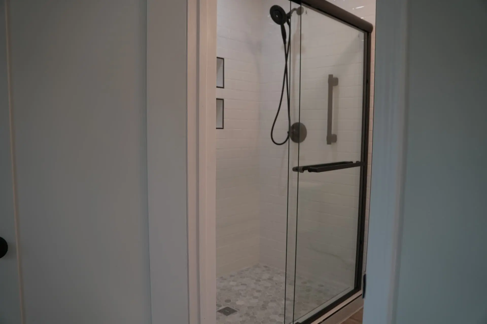 Glass-enclosed tiled shower with matte black fixtures