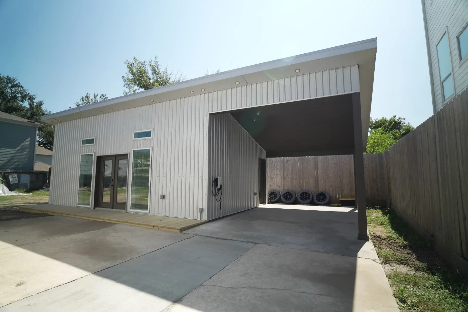 Metal-clad backyard tiny home with attached carport built by HTX Tiny Homes